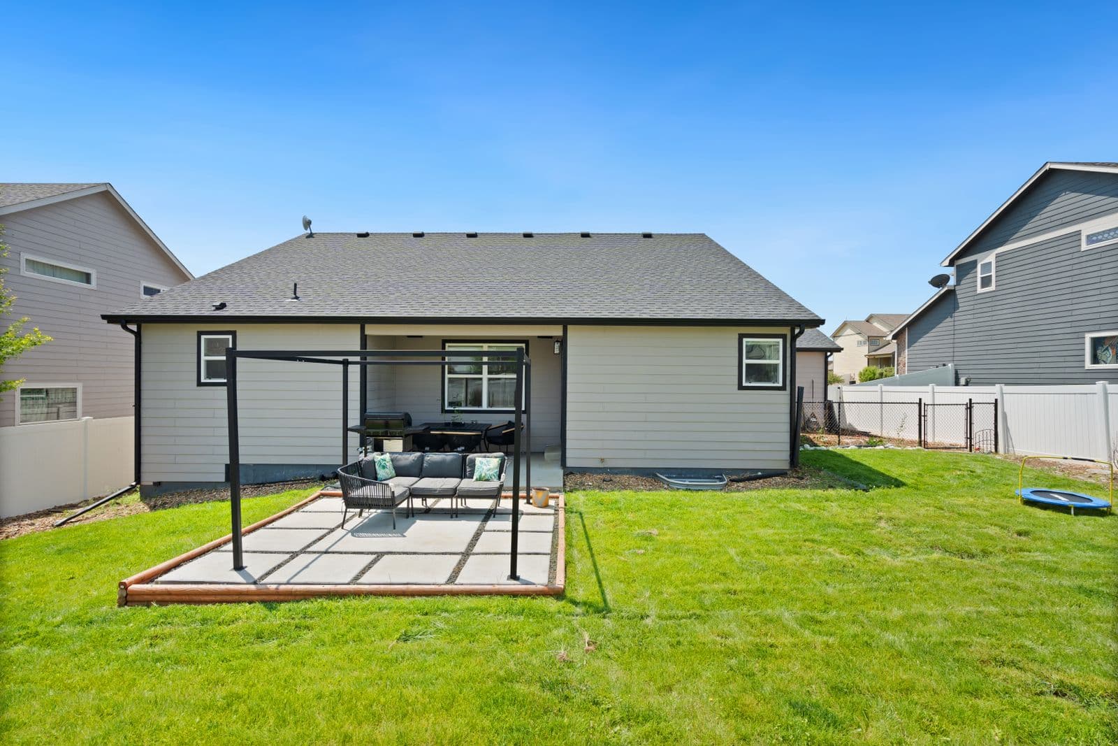 Paver patio with pergola and outdoor furniture in a backyard